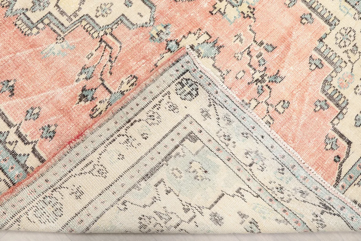 Flipped corner of the rug revealing the cotton foundation and the reverse side of the hand-knotted wool pile.