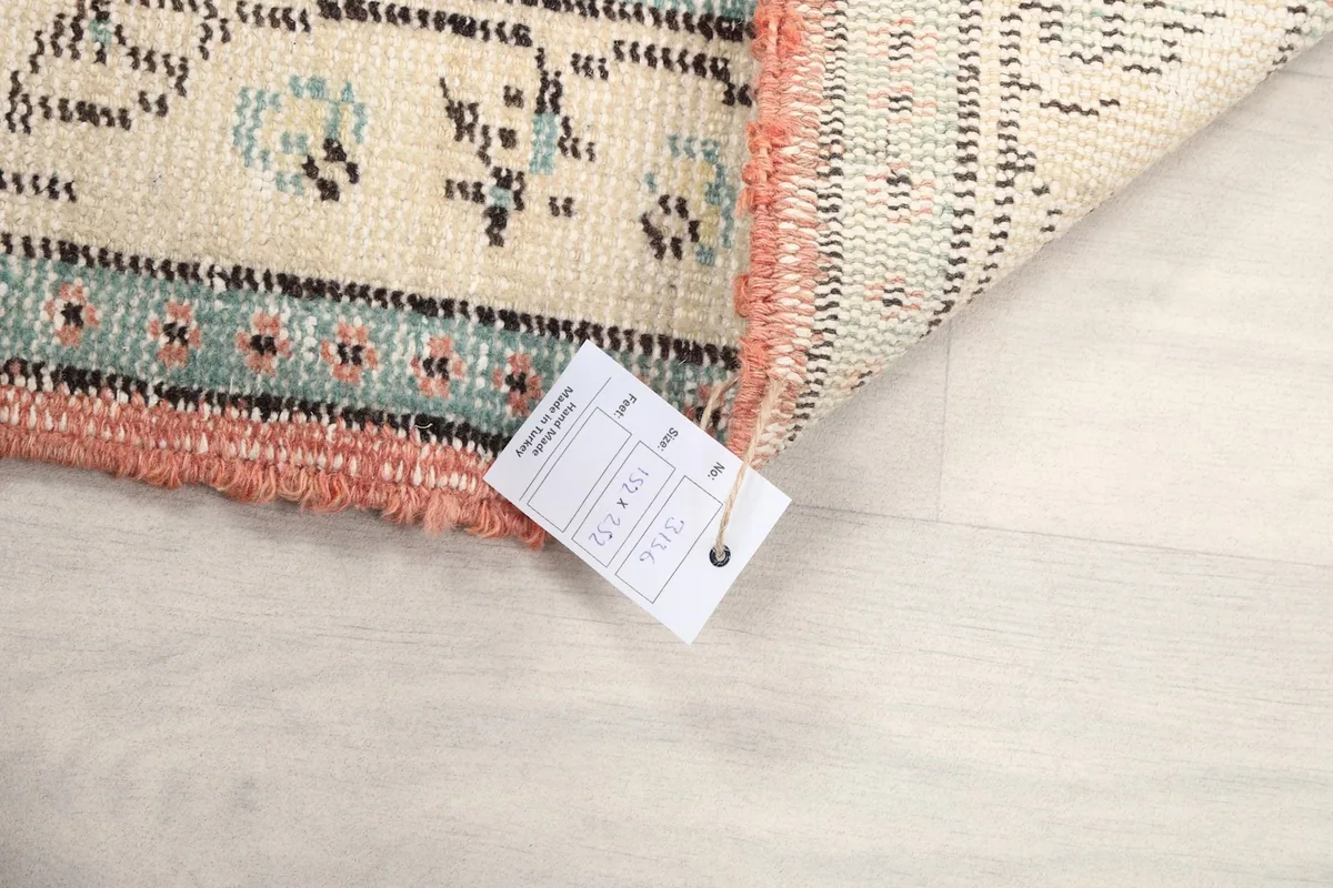 Corner of the rug with a size tag, showing the hand-knotted fringe and side finish.