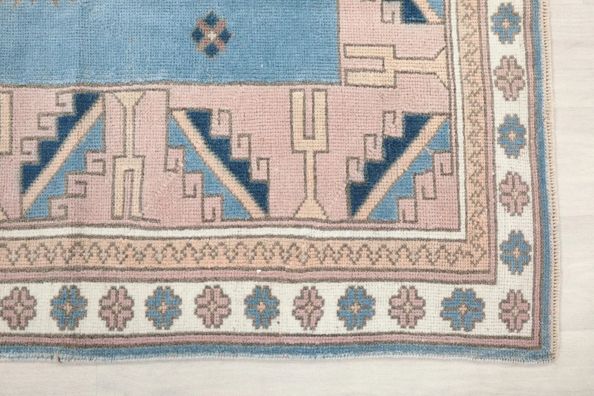 Detailed view of the corner of the rug, highlighting the rose border and navy geometric motifs