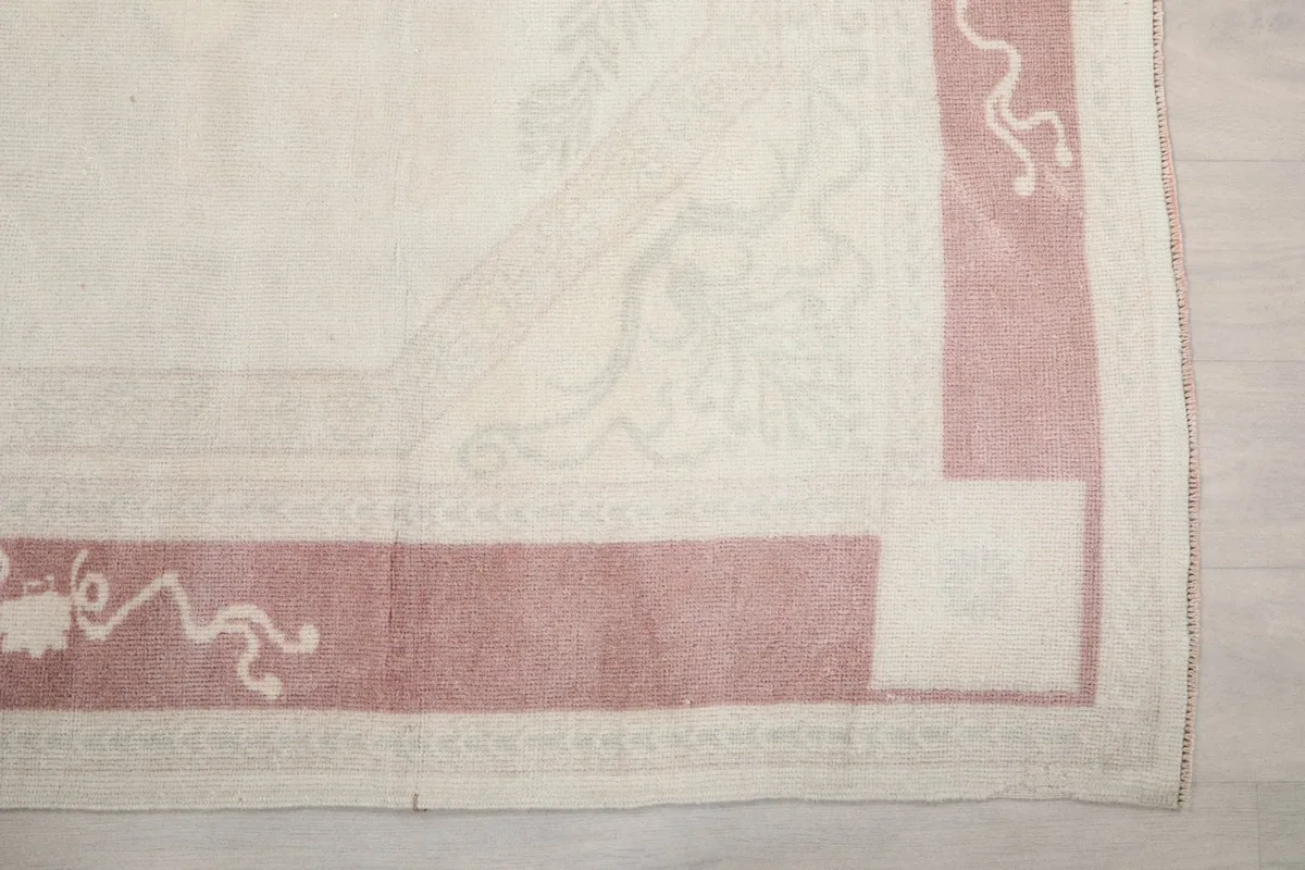 Detailed view of the rug's rose border and corner design with faded ivory field
