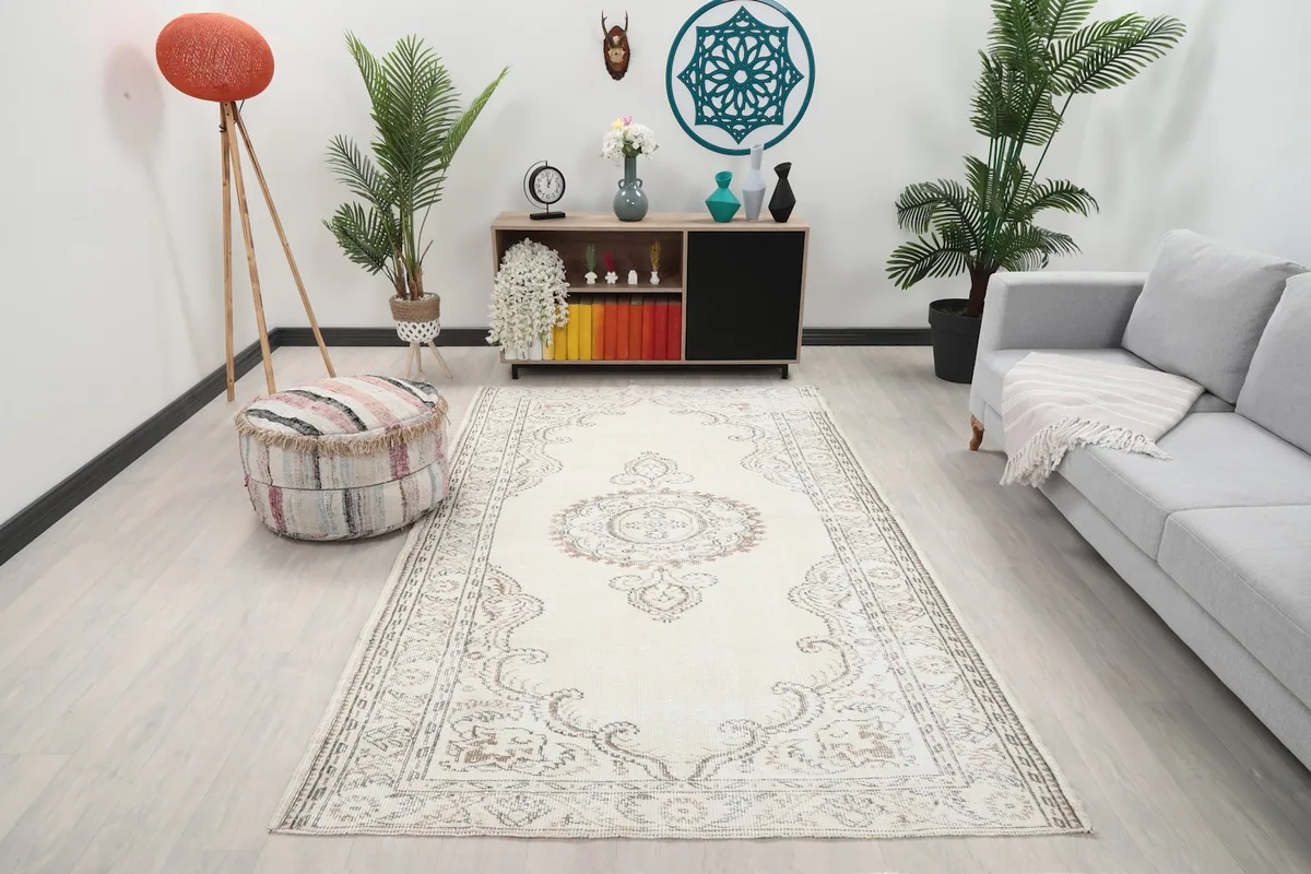 Ivory vintage rug displayed in a living room setting with a gray sofa and wooden furniture