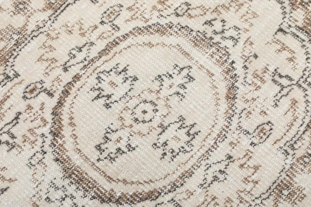 Extreme close-up of the central medallion's intricate, faded beige and tan patterns
