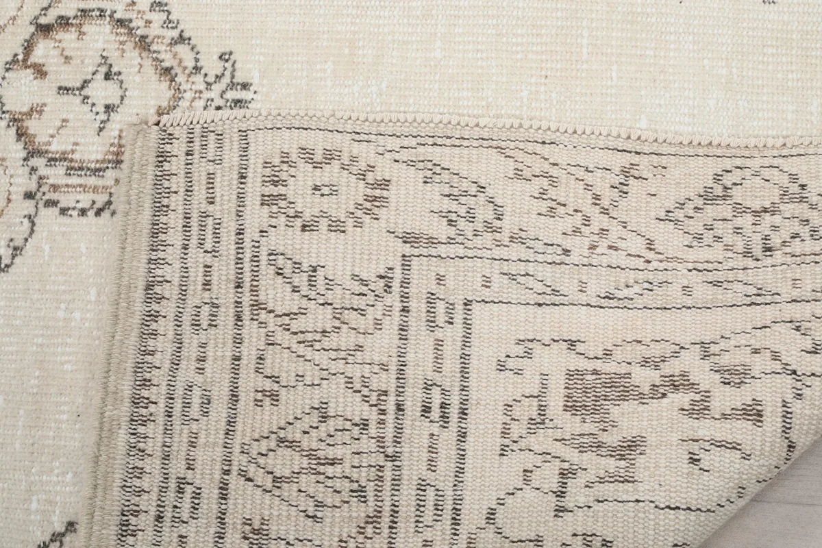Close-up of the rug's corner folded, revealing the hand-knotted wool pile and cotton foundation