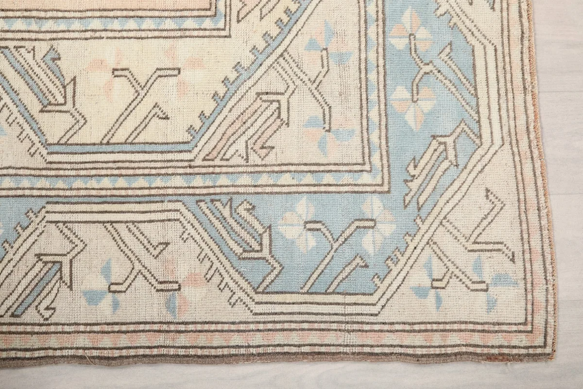 Detail of the blue geometric border and beige field of the rug