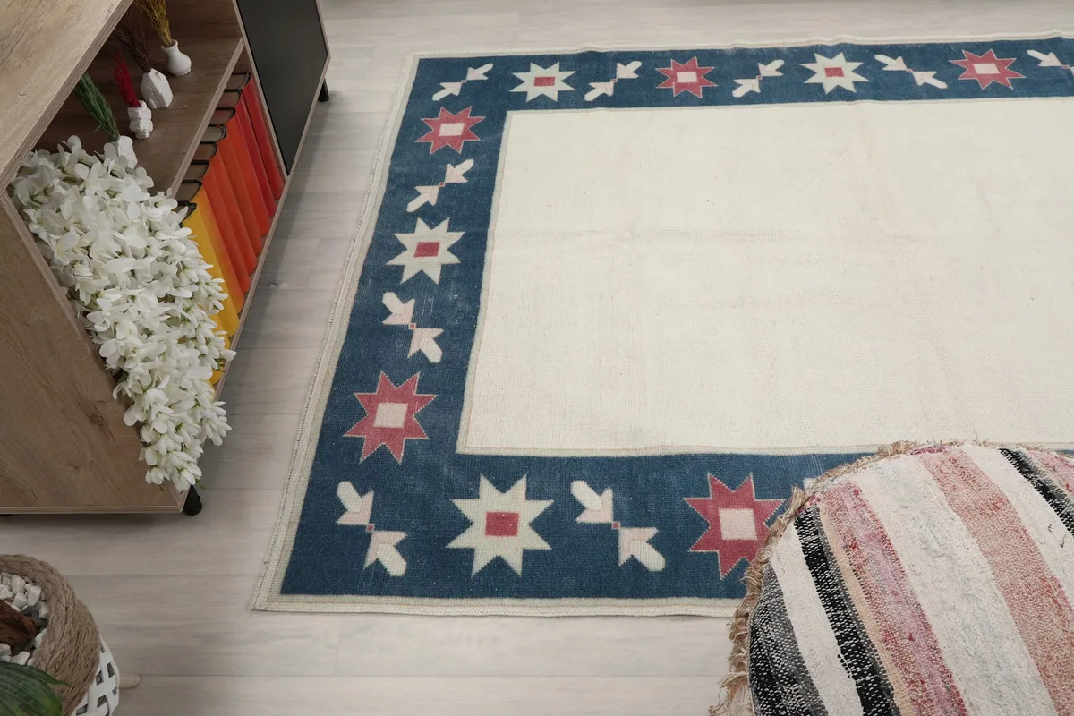 Angled view of the rug's side, showing its interaction with a decorative pouf