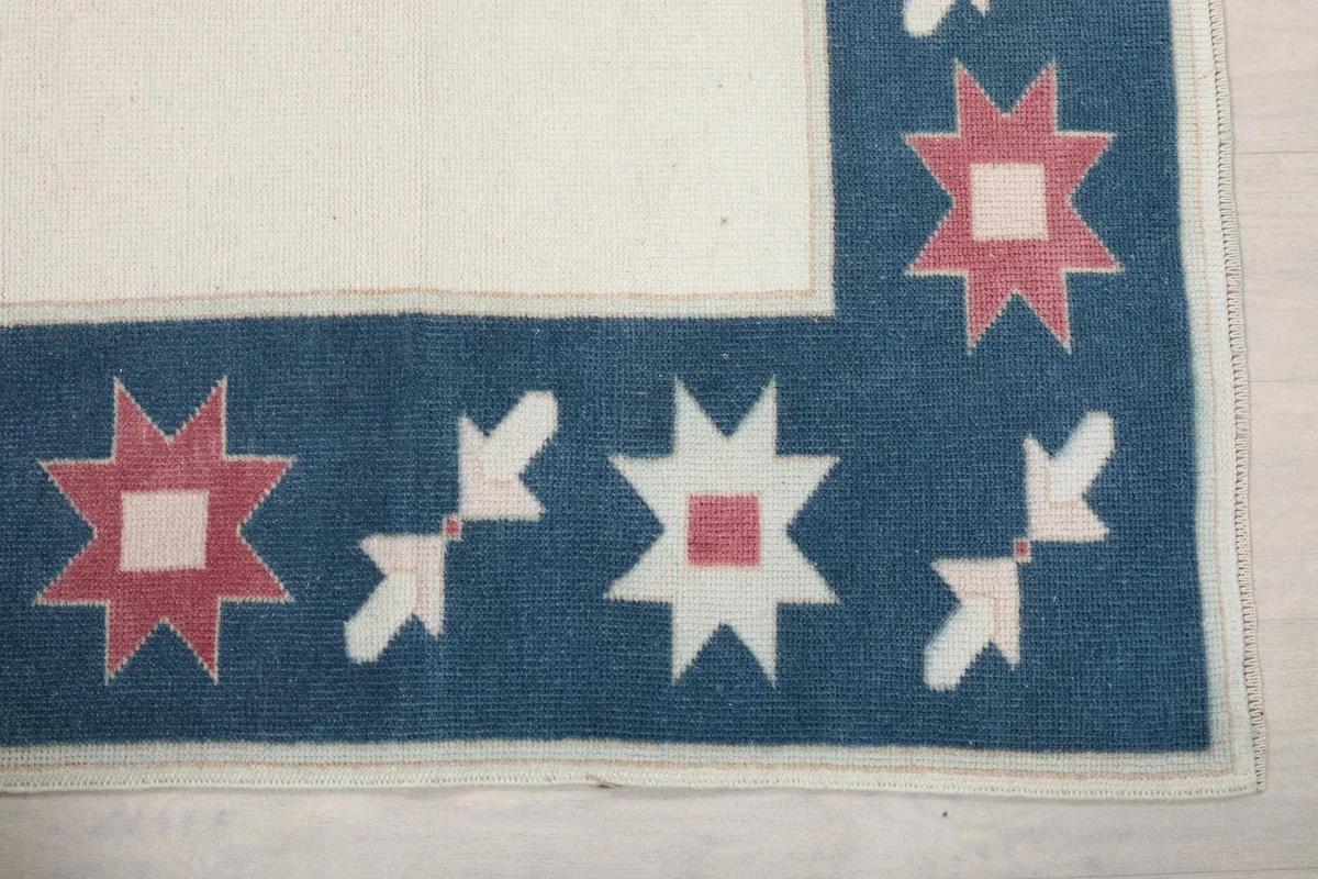 Detailed view of the corner border showing geometric star motifs in blue, ivory, and rose
