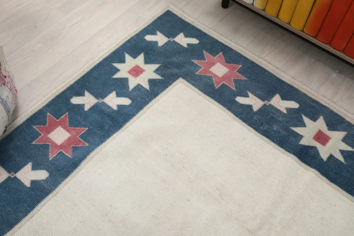 Corner detail of the blue border with ivory and rose geometric stars