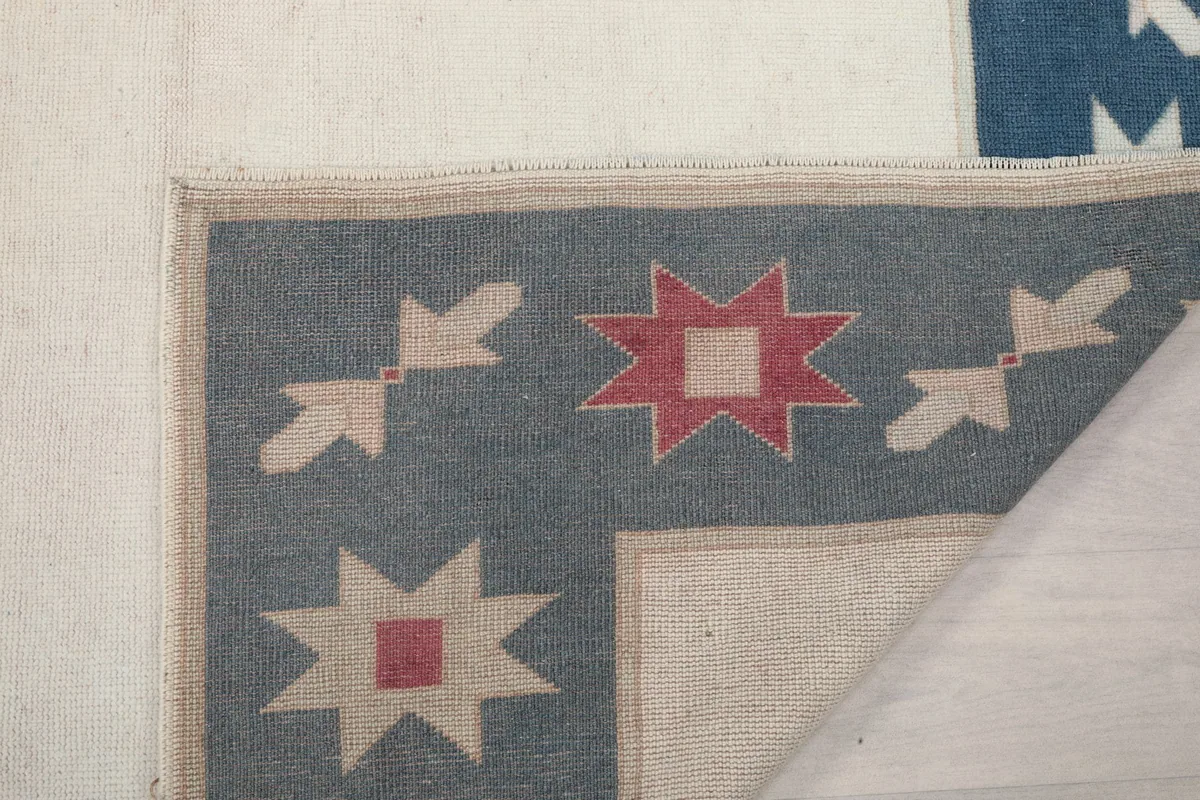 Corner of the rug folded back, showing the back weave and border design