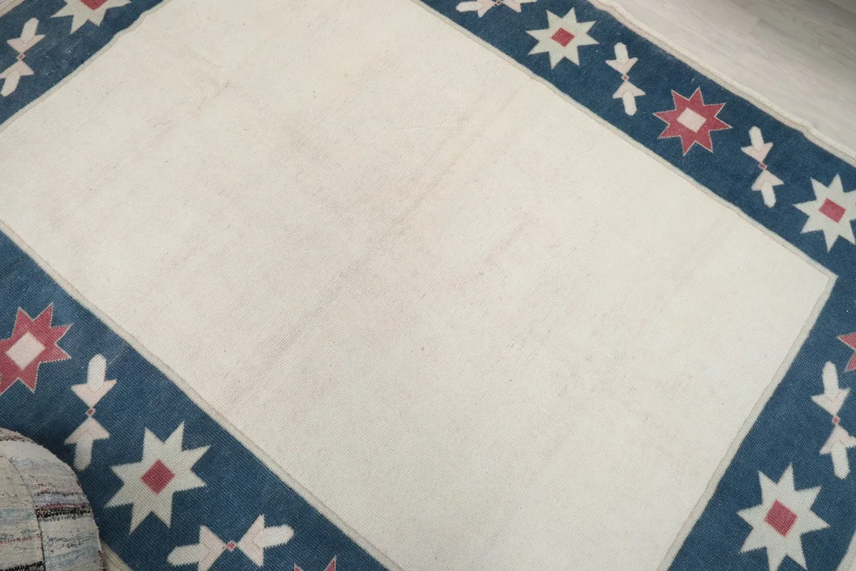 Overhead view of the rug's surface, highlighting the ivory field and patterned border