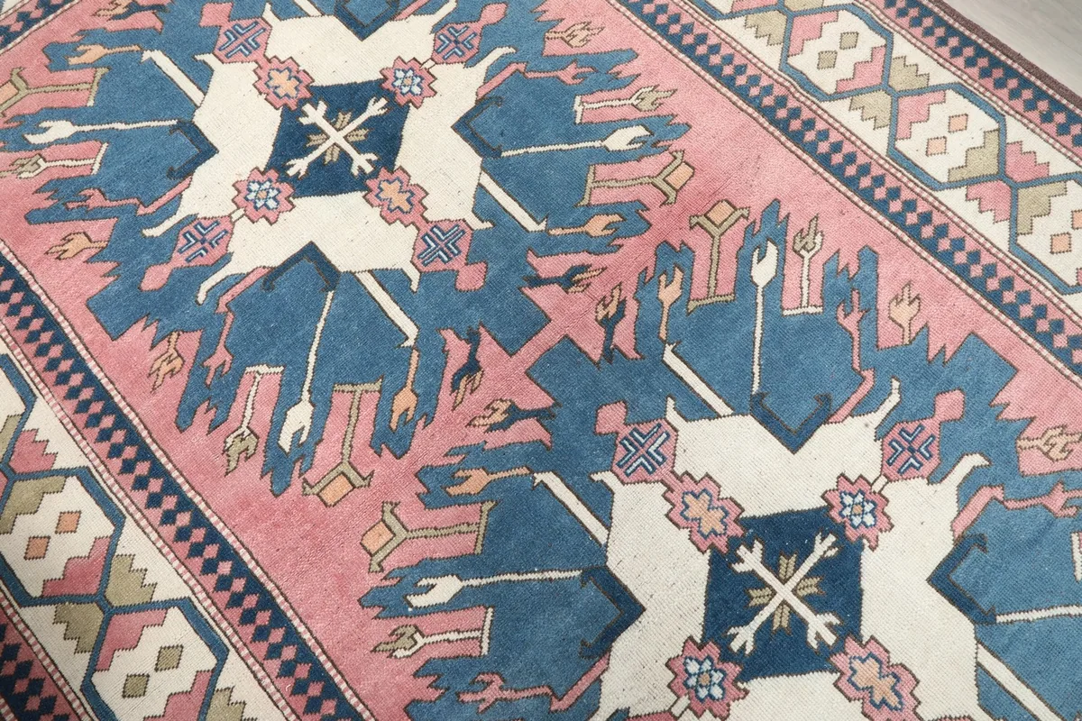Close-up of the central blue and ivory geometric motifs on the pink field