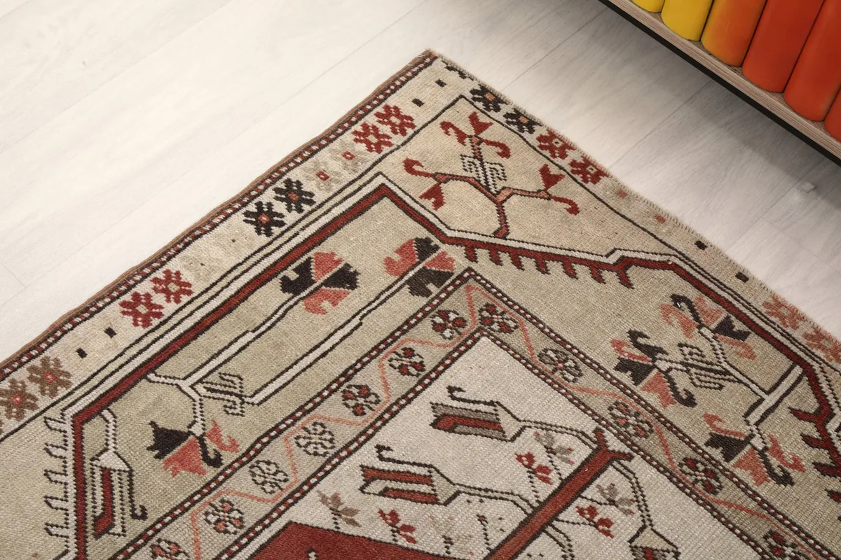Corner detail of the rug, showing intricate tribal patterns in beige and rust tones