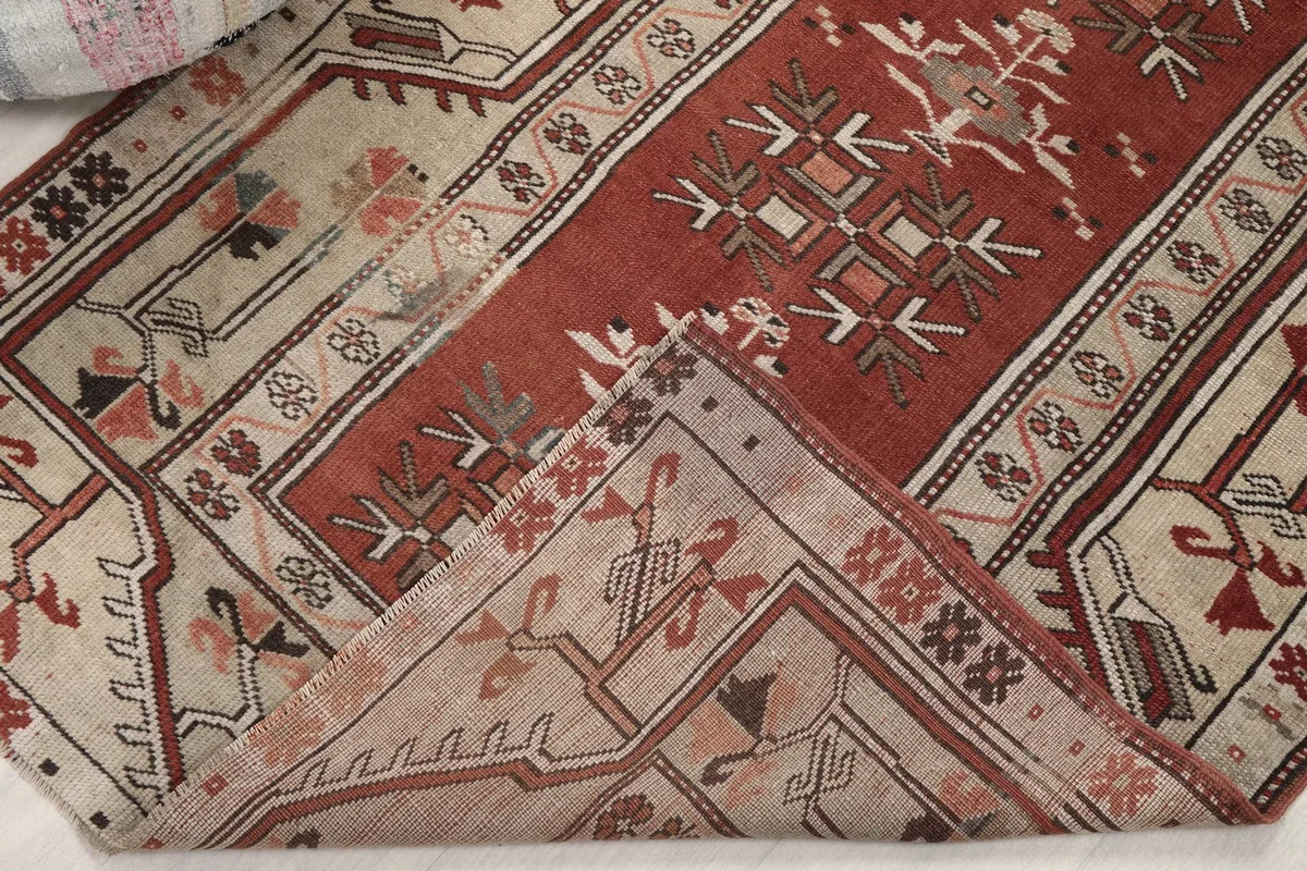 View of the rug folded back, revealing the reverse side and knotting detail