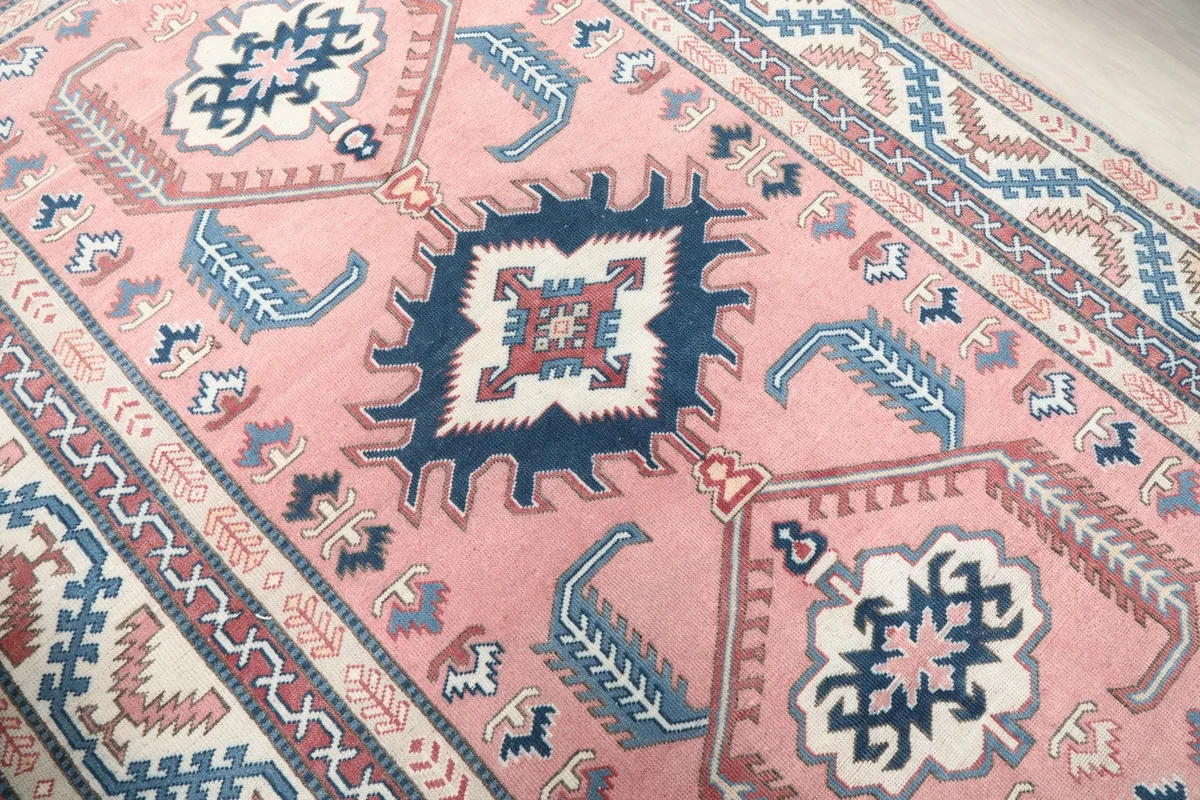 Detailed angled view of the pink field and the intricate navy and cream patterns within the medallion.