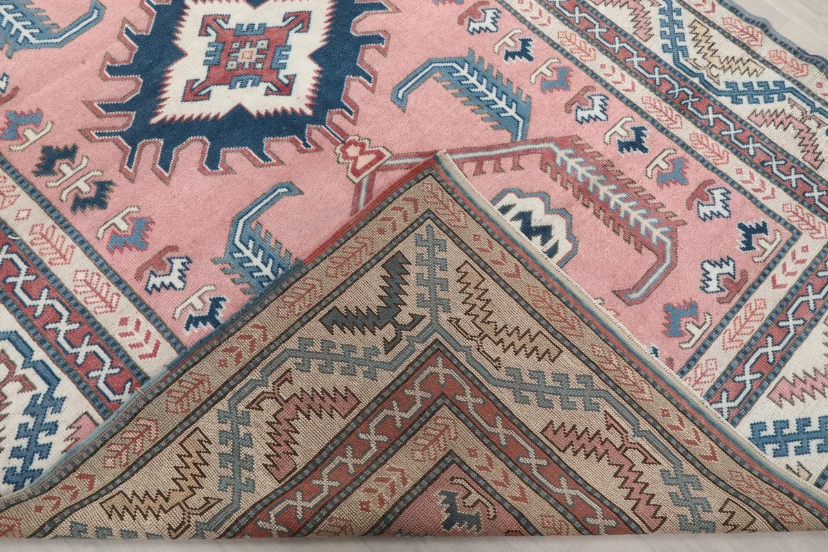 Corner of the rug folded back to show the hand-knotted wool pile and cotton foundation from the reverse side.