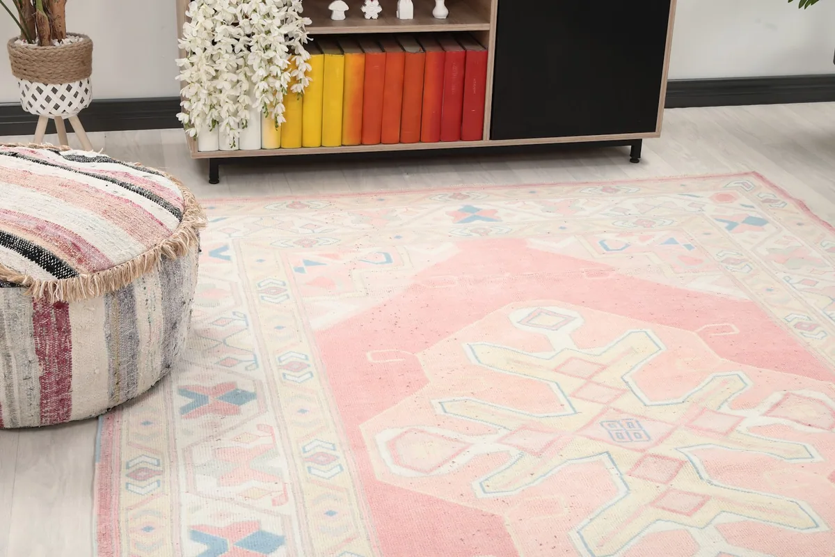Close-up view of the rug's geometric patterns and soft colors next to a pouf