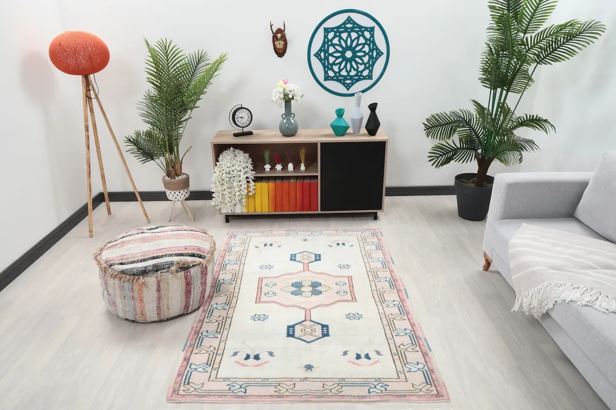 Vintage ivory rug in a living room setting with a light grey sofa and wooden cabinet