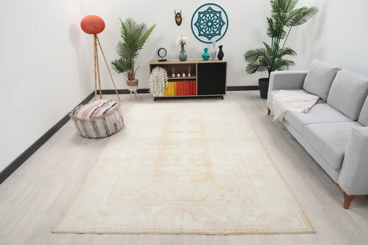 Ivory and beige floral geometric rug in a living room setting with a sofa and decor.