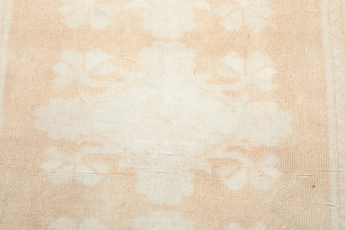 Close-up of the beige central floral motif, revealing the hand-knotted wool pile.