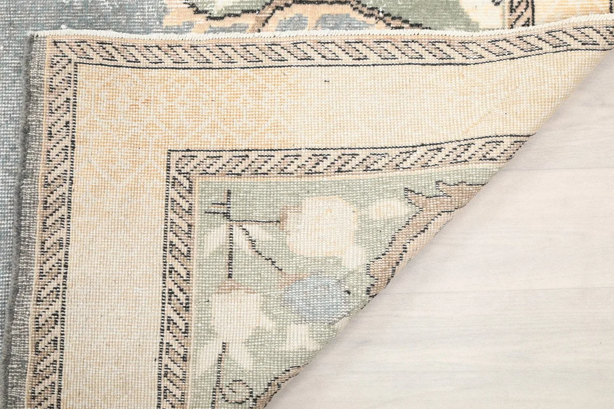 Underside of the gray rug showing the cotton foundation and knotting structure