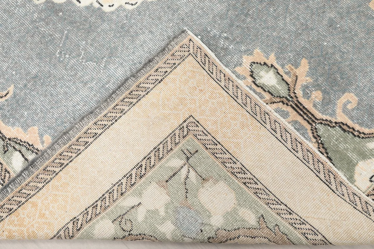 Folded corner of the gray rug revealing the back of the hand-knotted wool pile