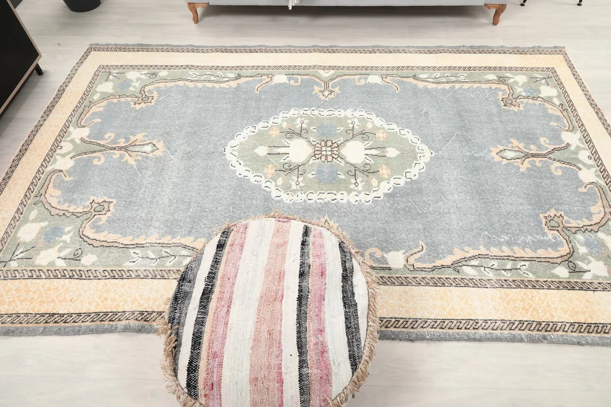 Full overhead view of the gray rug, centered with a striped pouf