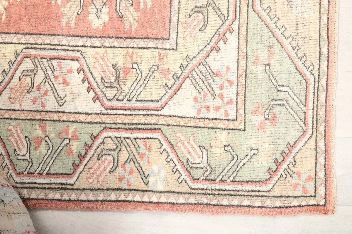 Detail of the rug's green and beige outer border with intricate tribal patterns