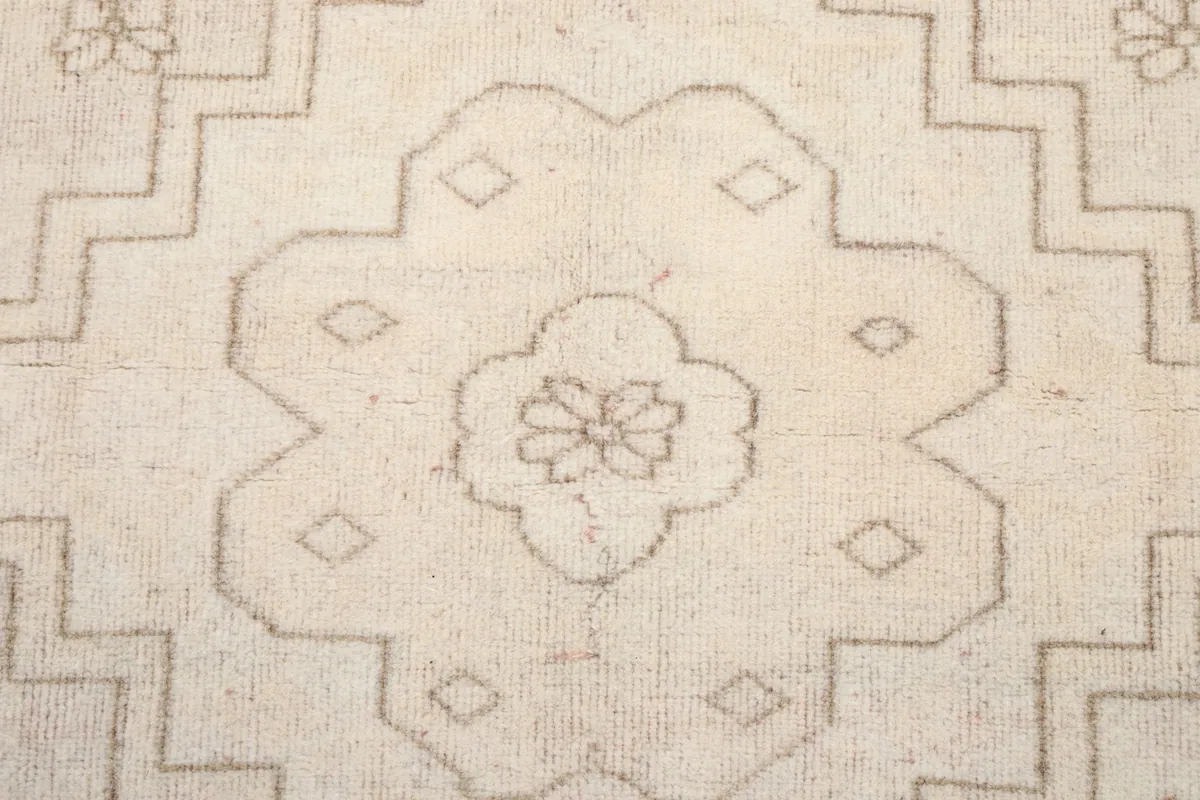 Close-up of the central medallion design, featuring a stylized floral element within geometric shapes.