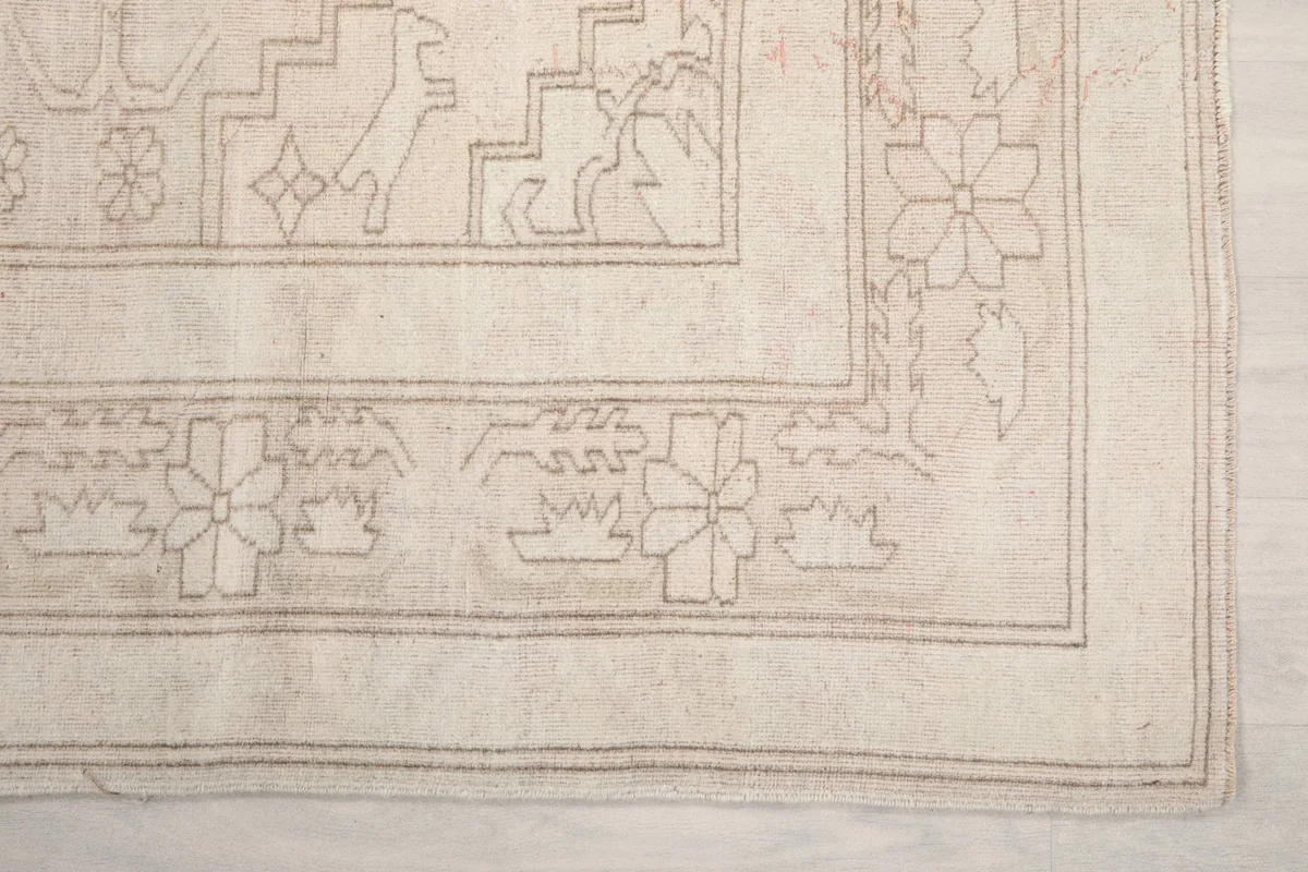 Detail of the rug's border, showcasing the hand-knotted floral and geometric motifs.