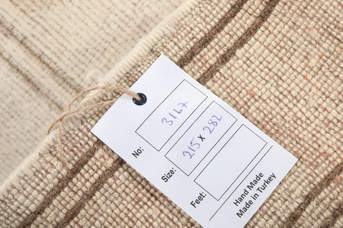 Close-up of the rug's back with a tag showing 'Hand Made in Turkey' and size details.