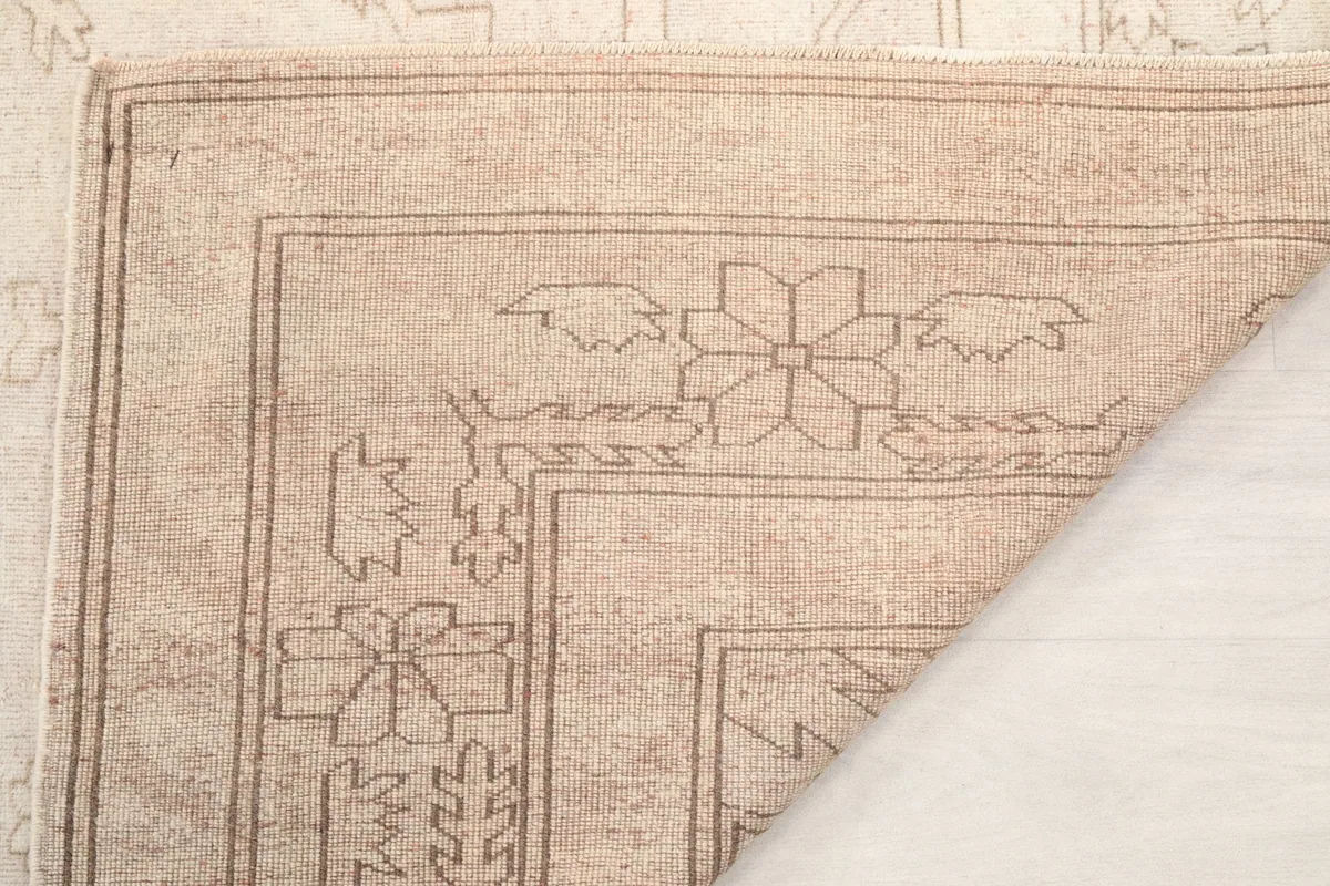 Another view of a folded corner, highlighting the hand-knotted construction and border details.