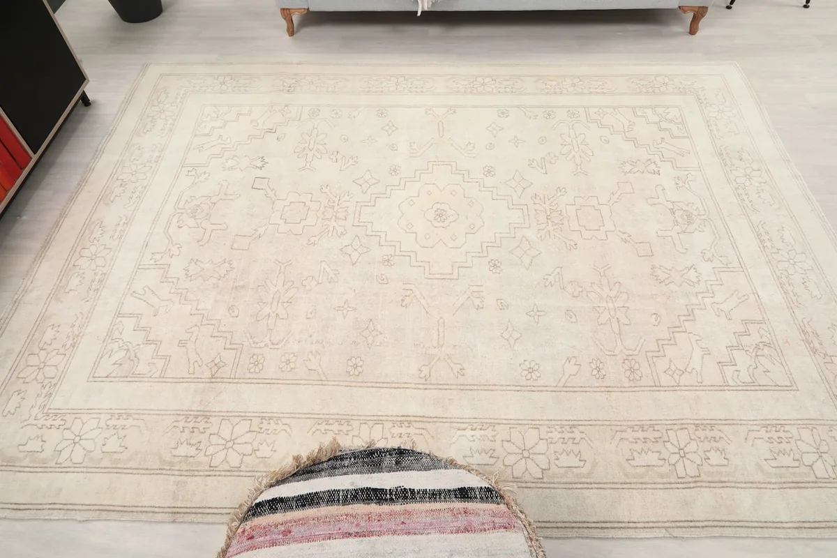 Overhead view showing the full expanse of the 7'1" x 9'3" ivory rug on a light floor.