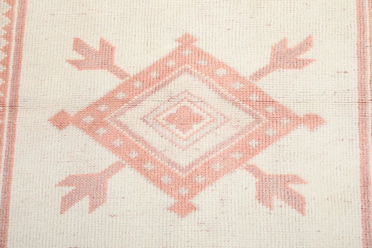 Extreme close-up of a central geometric diamond motif in rose and ivory