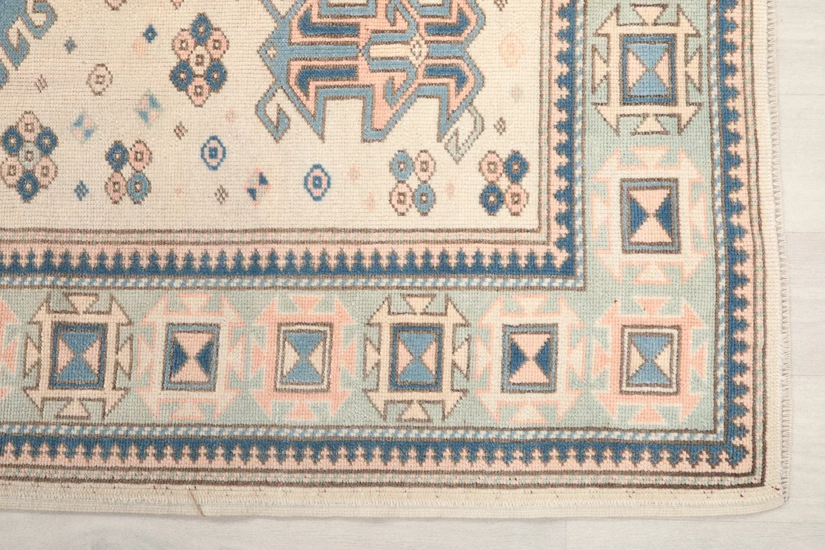 Detailed view of the intricate blue and rose border designs on the vintage Anatolian rug.
