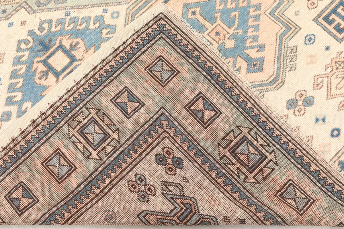 View of the rug folded to show the wool pile on cotton foundation and the back of the weave.