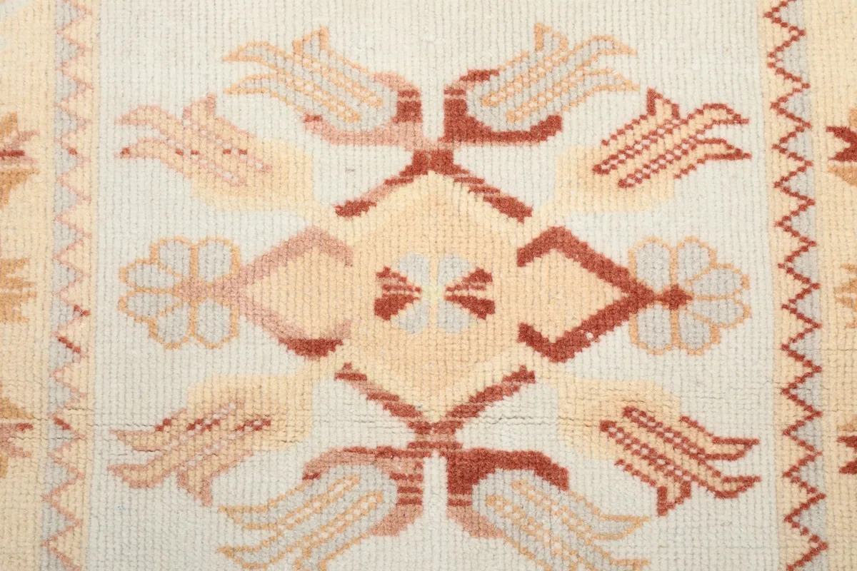 Close-up detail of the central geometric pattern in ivory, orange, and rust colors