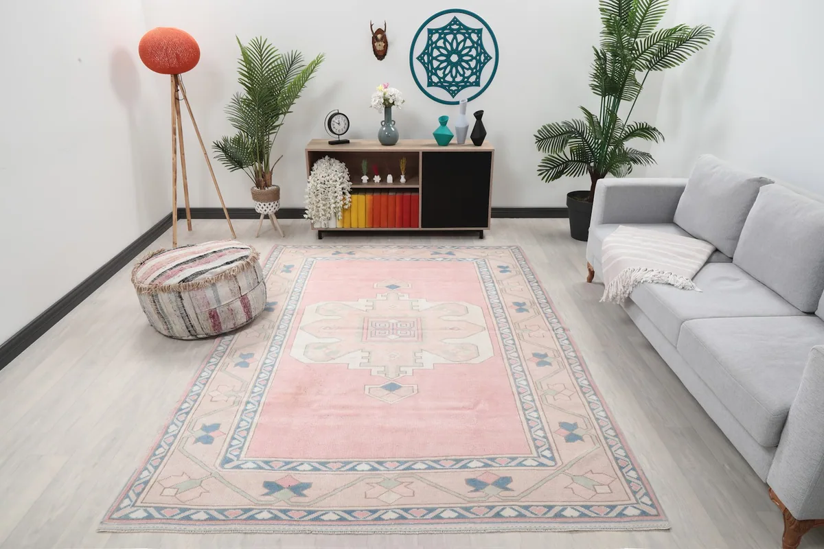 Vintage pink beige rug displayed in a bright living room setting with a gray sofa.