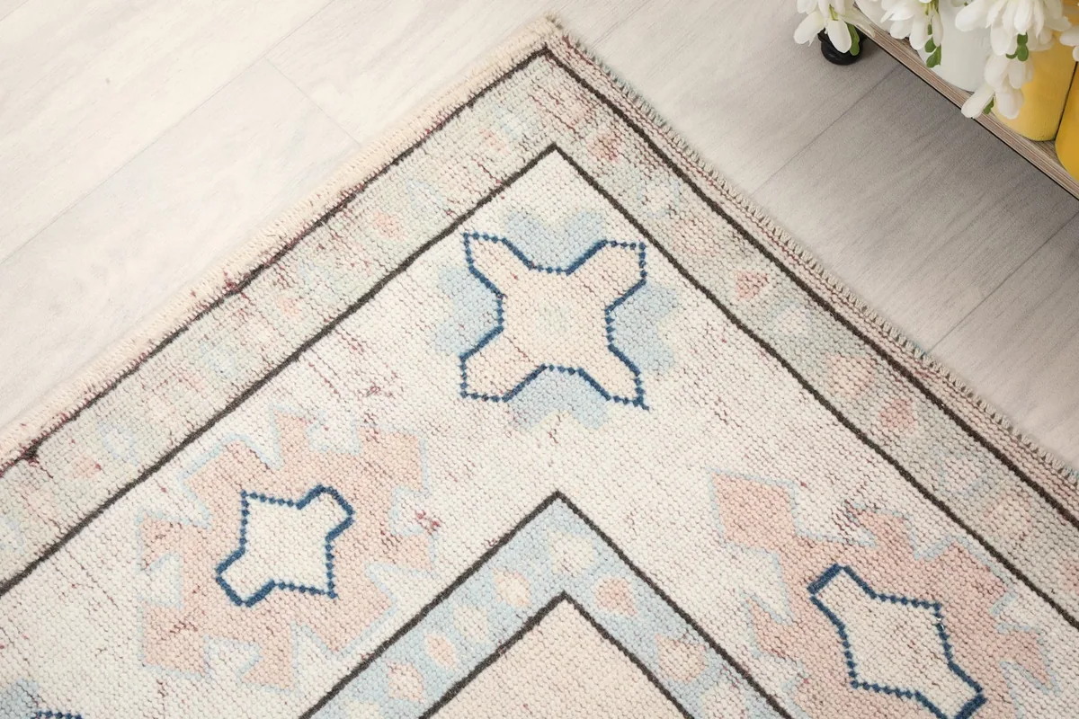 Detail of the rug's outer border design with blue cross-like geometric elements