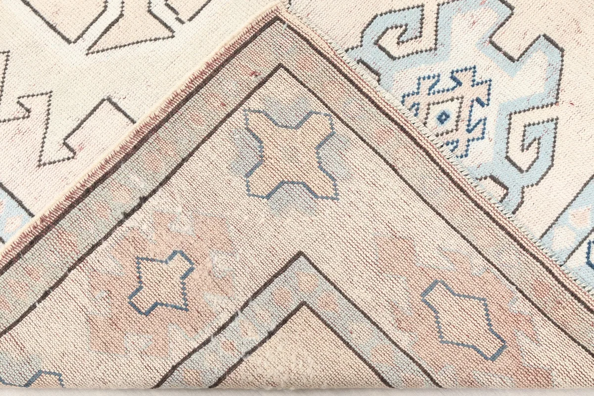 Corner of the rug folded back, revealing the reverse side and foundation