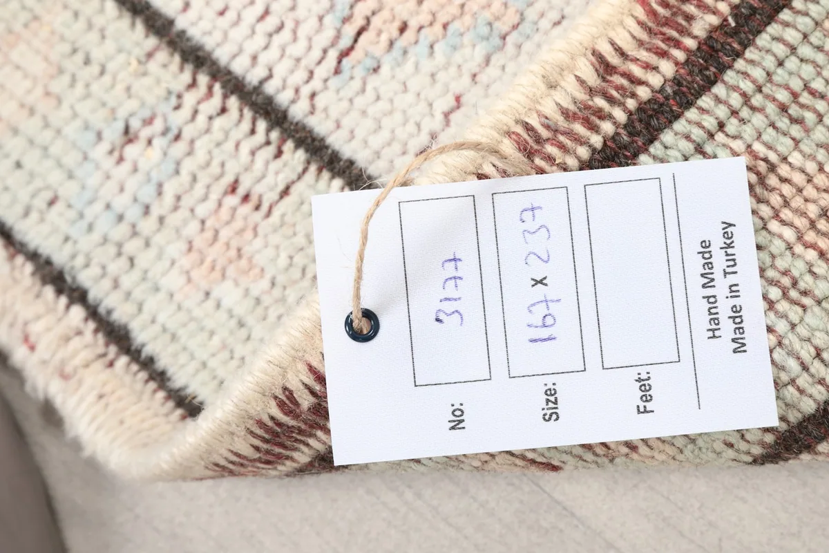 Product tag attached to the rug, showing its size 167x237 cm and hand-made origin