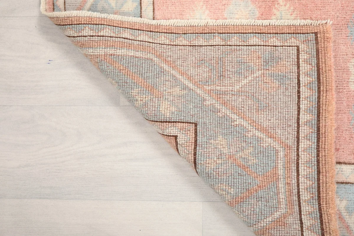 Corner of the rug folded back, showing the wool pile and cotton foundation