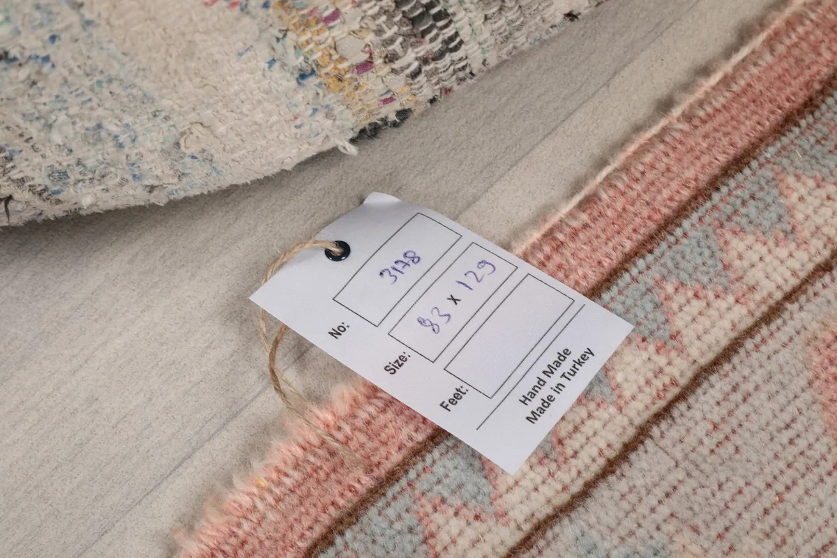 Tag showing the rug's dimensions in centimeters and feet, verifying hand-made origin