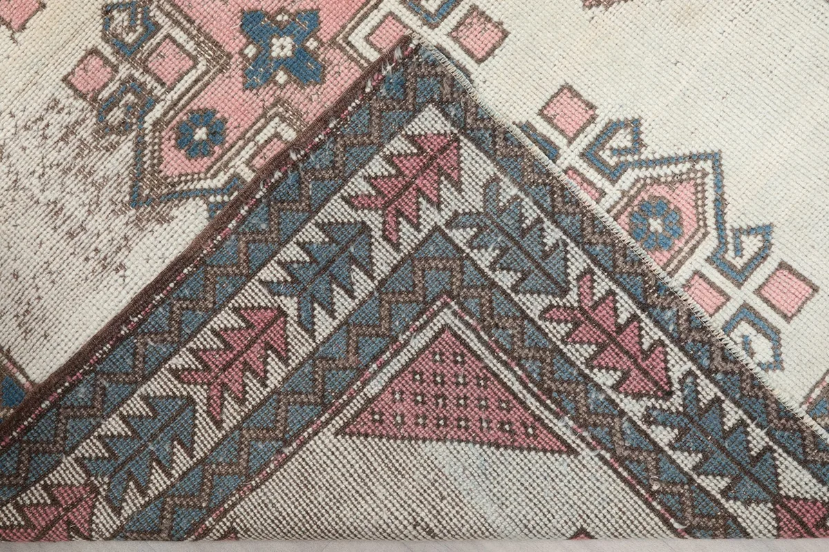 Corner of the rug folded back, revealing the cotton foundation and reverse side of the knotting