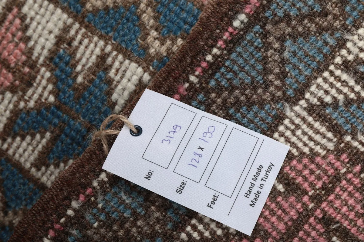 Close-up of the product tag attached to the rug, showing size 128x190 cm and origin Turkey