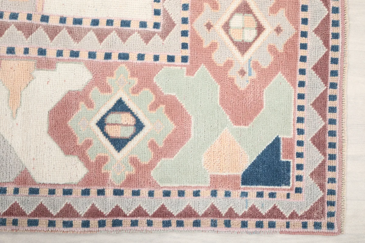 Detail of the border design, showing rose, blue, and gray geometric motifs of the Ivory Rose Geometric Anatolian Rug