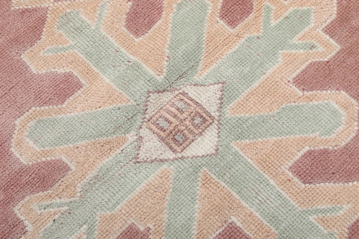 Close-up of the central motif, showing the texture and color variations in rose, olive, and ivory