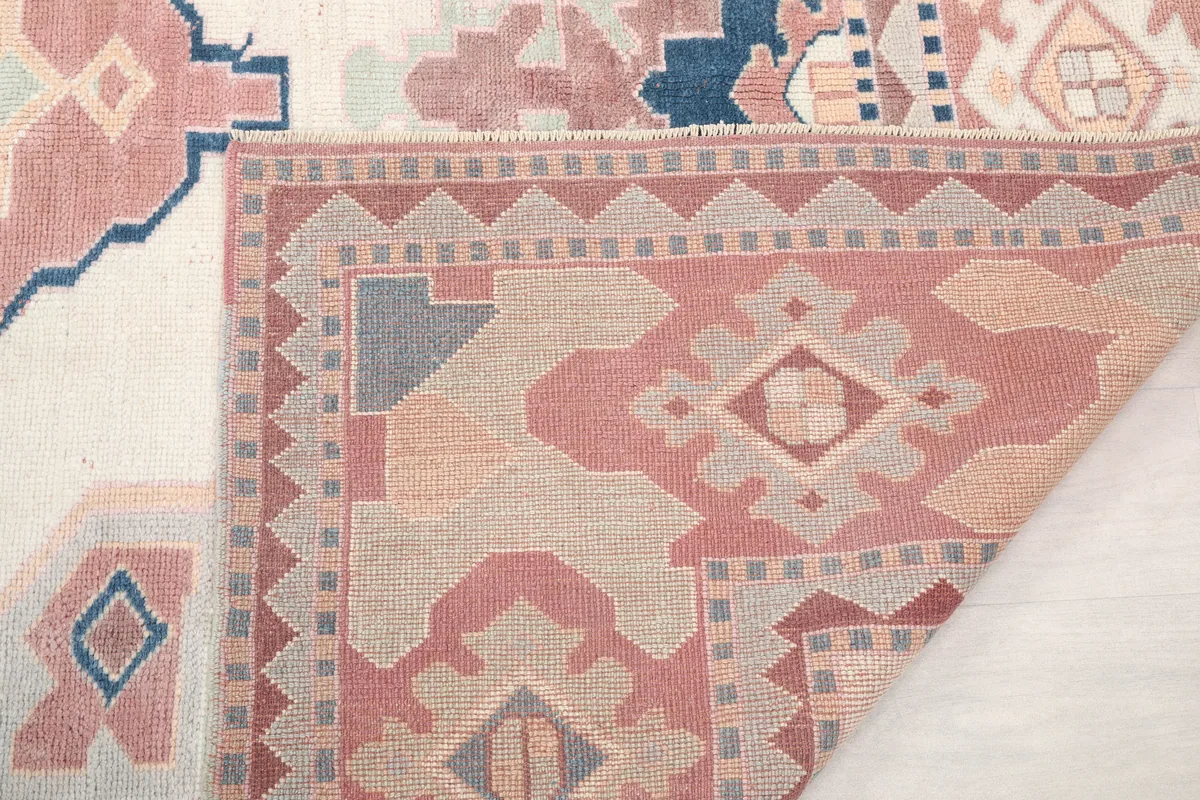 Close-up of a folded corner of the Ivory Rose Geometric Anatolian Rug, showing the pile and foundation