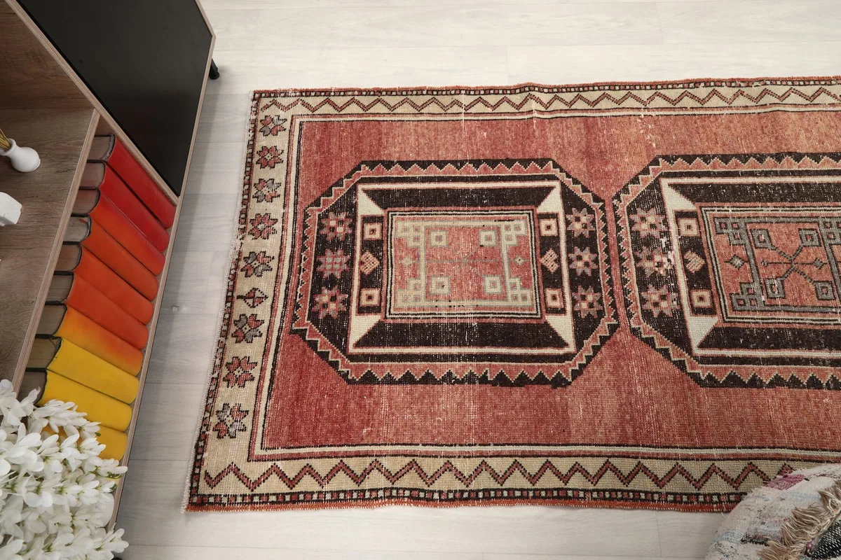 Angled view looking down the length of the rust runner rug with its distinct medallions.