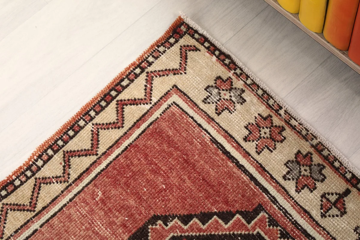 Corner detail of the rug's border, featuring beige, rust, and black geometric elements.