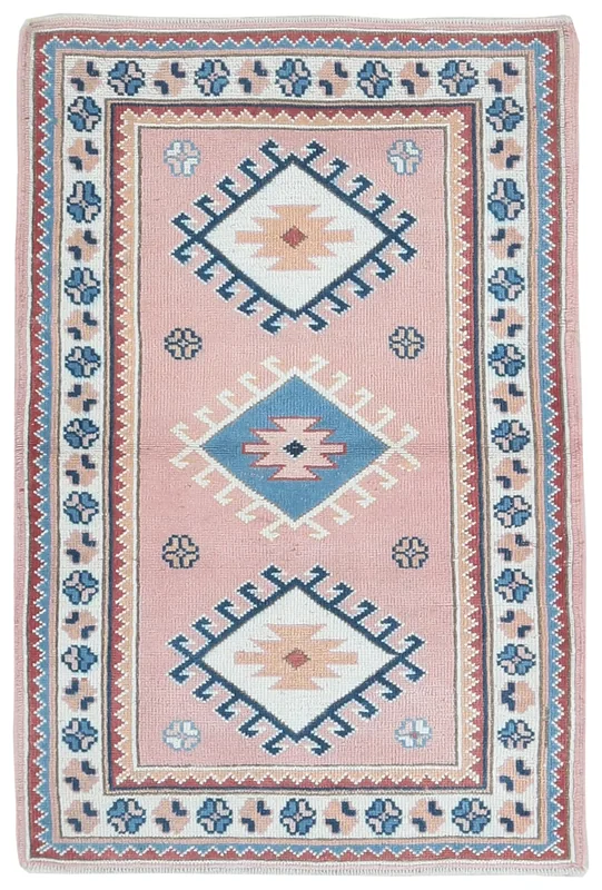 Top view of a vintage Anatolian rug with pink field and blue, ivory, rust geometric patterns