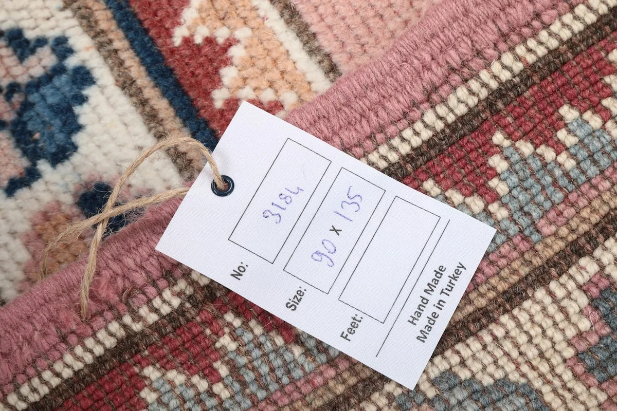 Tag on the rug displaying size in centimeters and feet, confirming handmade in Turkey origin